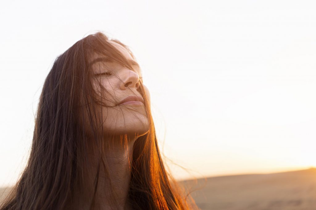 Mujer con expresión serena disfrutando del sol, símbolo de bienestar tras superar la dependencia emocional – Ana Serrano Psicóloga.